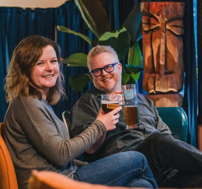 Amy and Matt smiling and sharing a beer at Beachcrest Brewing